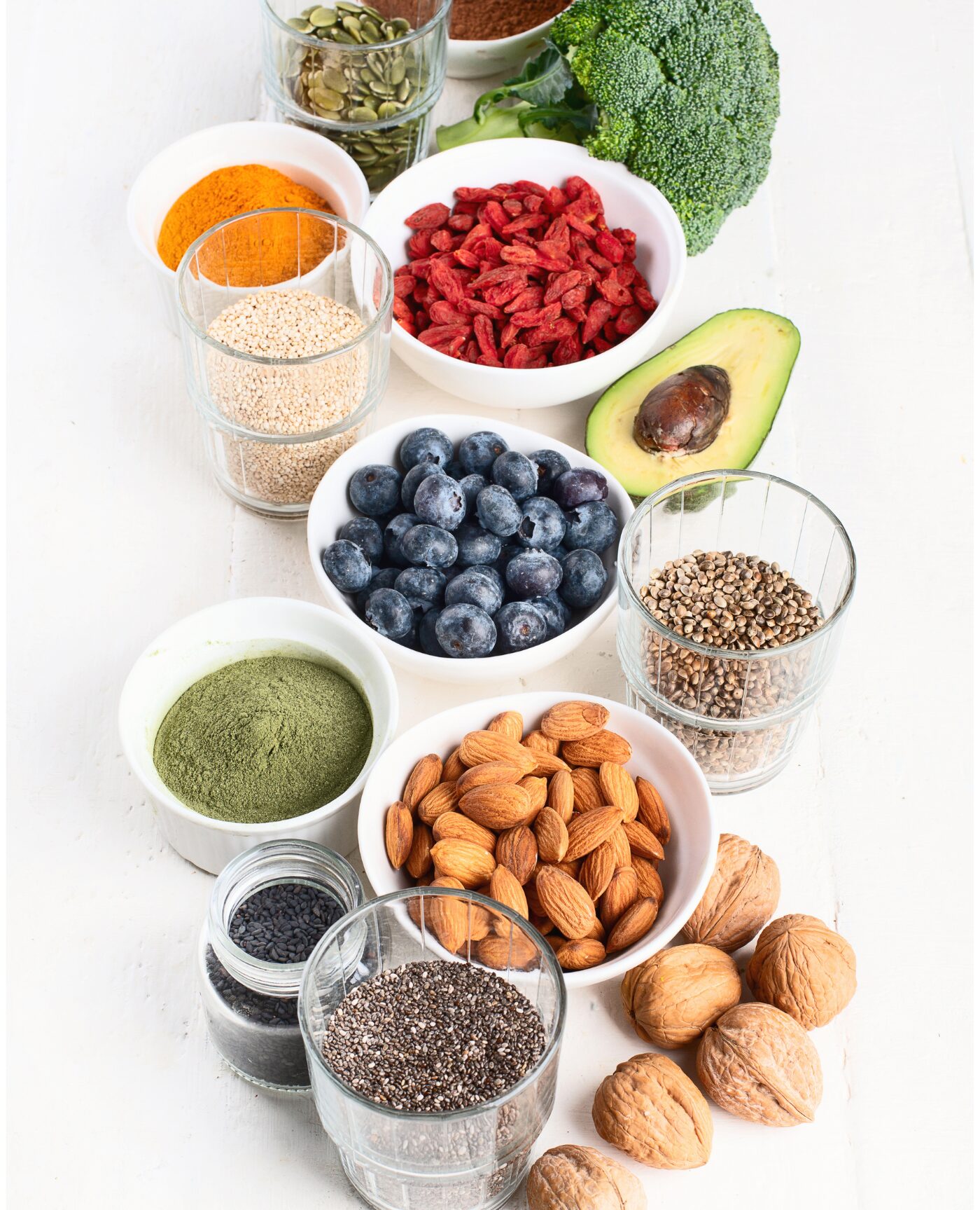 Various healthy foods in bowls such as chia seeds, blueberries, almonds, etc.